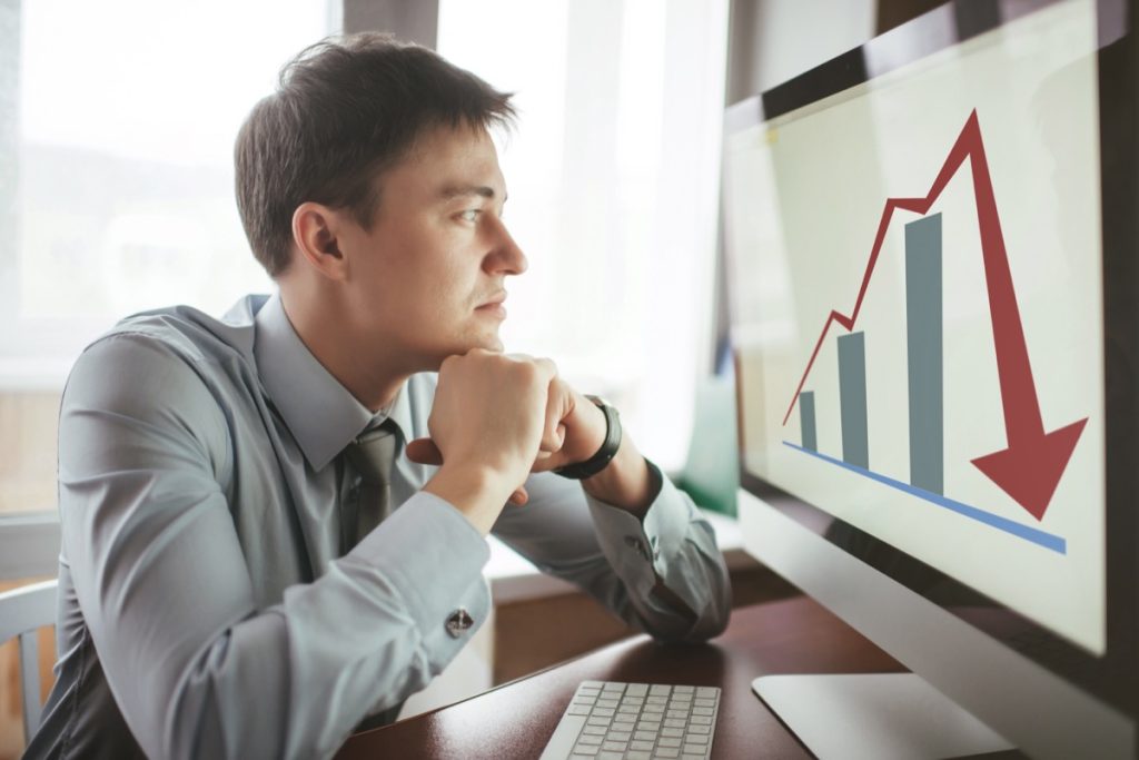 Man looking at graph on computer trending downward
