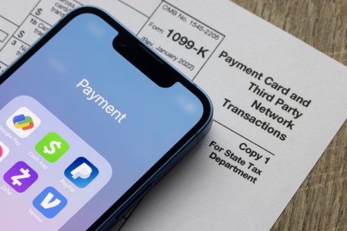 Portland, OR, USA - Jan 5, 2022: Payment apps like PayPal and Venmo are seen on an iPhone on top of Form 1099-k. Third-party payment apps now have to report transactions more than USD600 to the IRS.