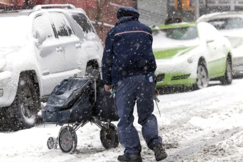 BRONX, NEW YORK - JANUARY 7: Mail man pushes mail carriage during snow storm. Taken January 7, 2017 in New York.
