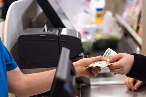 Woman giving cash when paying at a supermarket