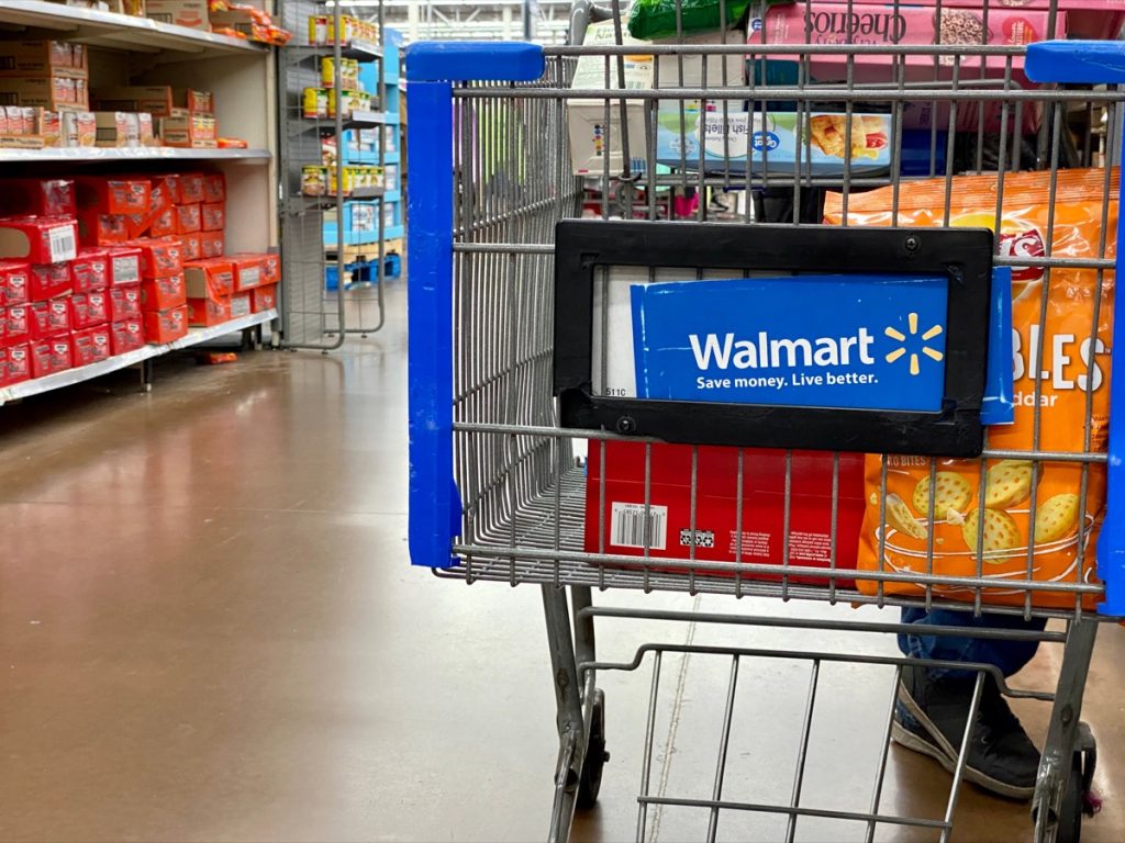 Closeup of Walmart shopping cart in the middle of an aisle with some items already inside.