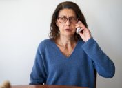 A senior woman on the phone with a suspicious or concerned look on her face