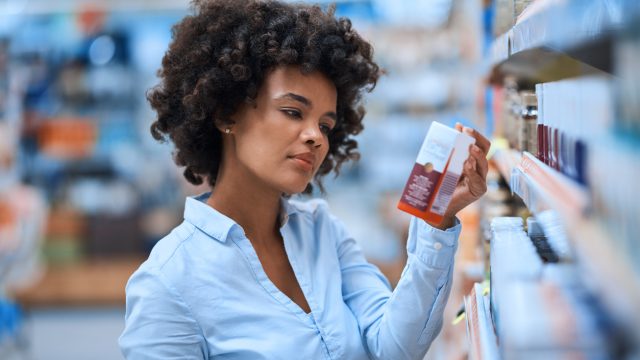 A young woman looking at an OTC medicine in the pharmacy aisle
