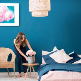 Young woman decorating bedroom with flowers at home.