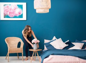 Young woman decorating bedroom with flowers at home.