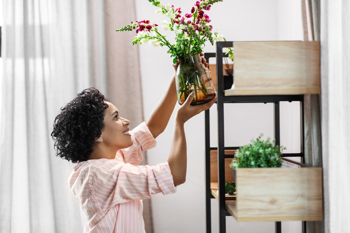 happy smiling woman placing flowers to shelf