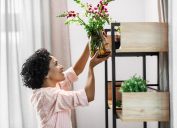 happy smiling woman placing flowers to shelf