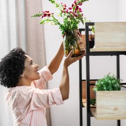 happy smiling woman placing flowers to shelf