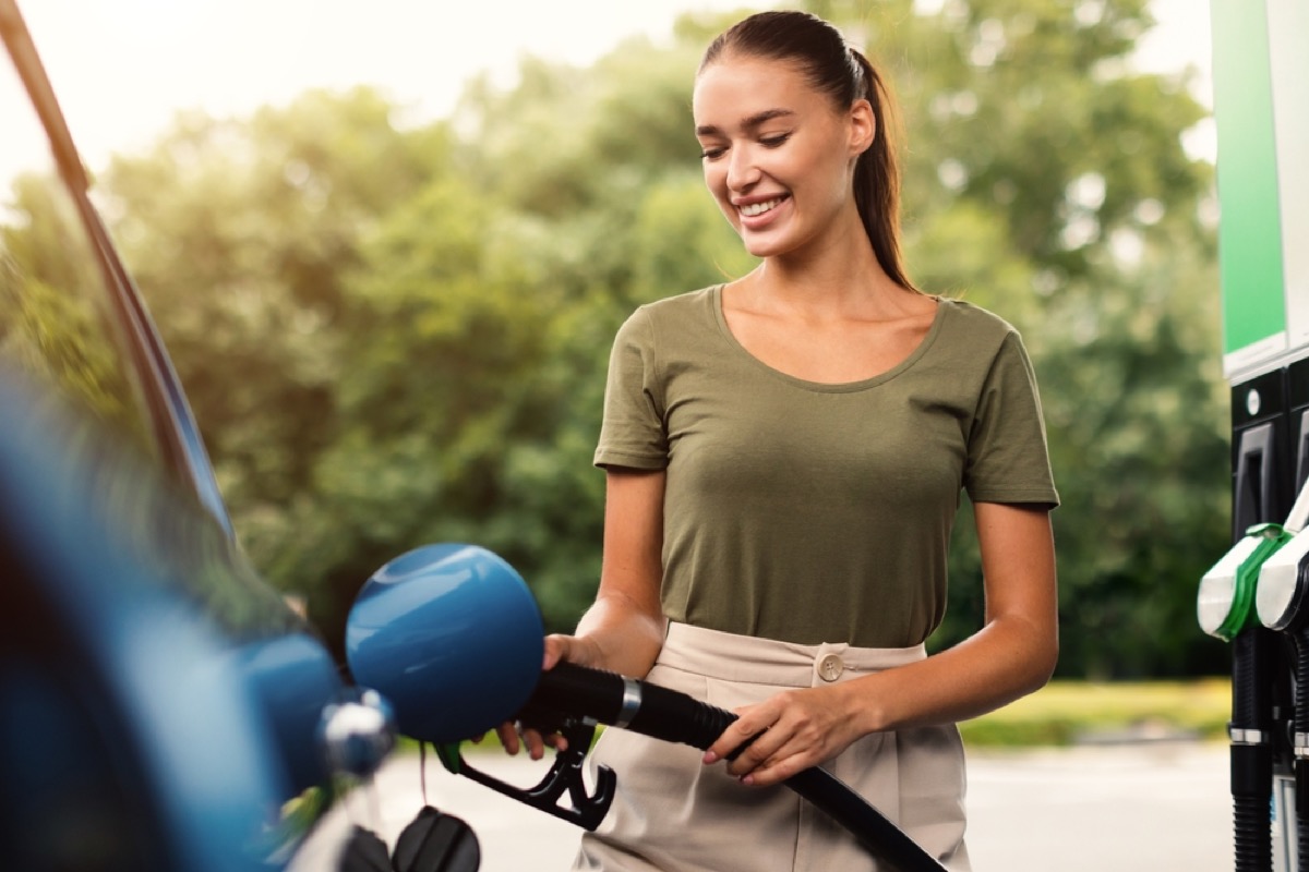 woman smiling while filling gas