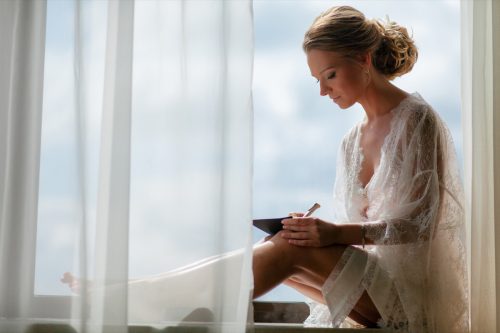 Bride in the lace robe is writing a vow for the wedding