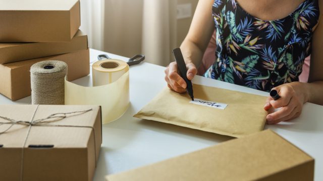 woman writing on a label on an envelope while mailing out packages