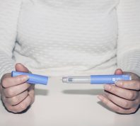 A close up of a person holding a diabetes or weight loss drug injection device
