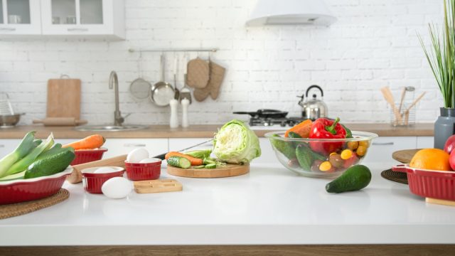 Modern stylish kitchen interior with vegetables and fruits on the table . Bright white kitchen with household items . The concept of a healthy lifestyle.