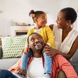 Mother, father, and small daughter laughing and playing in living room