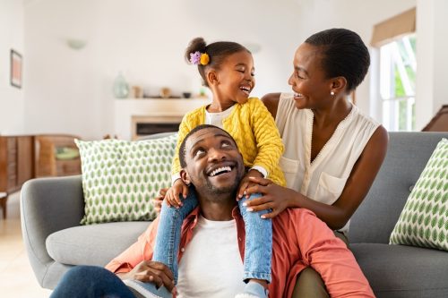 Mother, father, and small daughter laughing and playing in living room