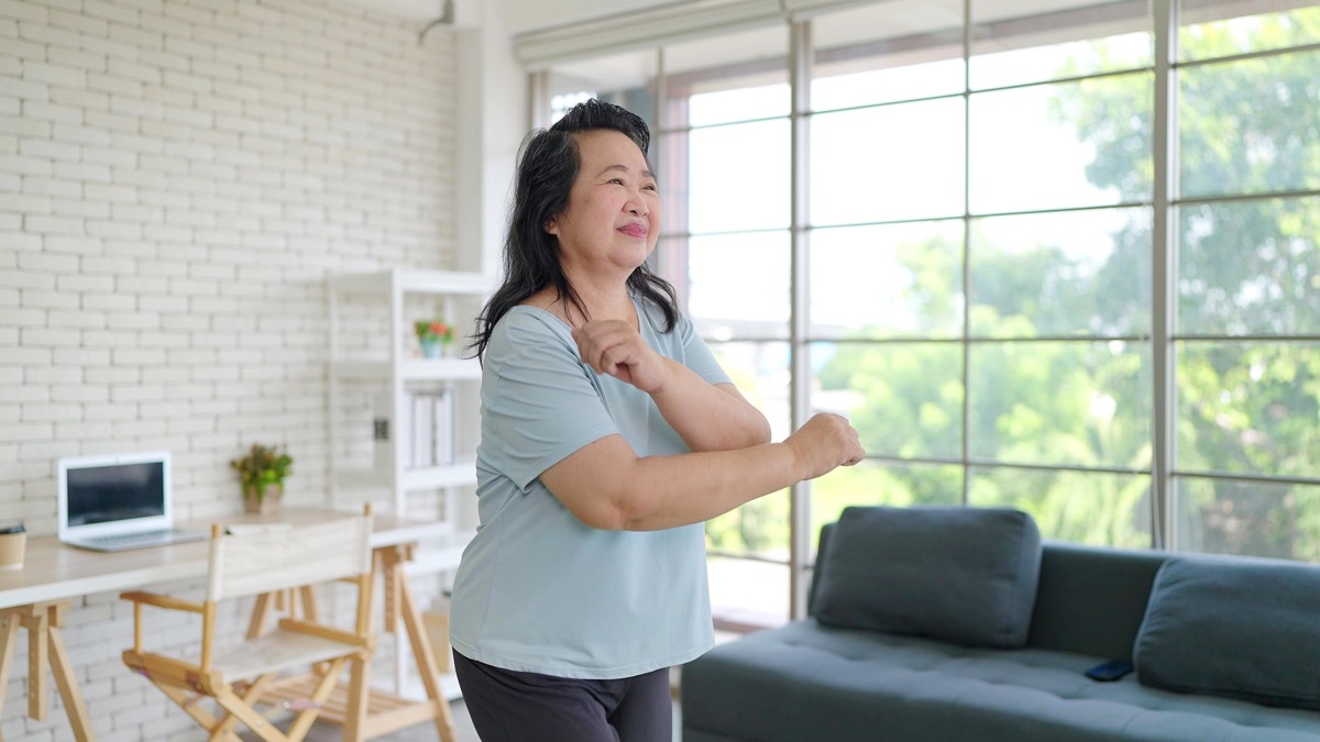 Senior Asian woman doing warm up exercises at home. Active elderly woman doing arms exercise at home. Elderly Sporty people lifestyle concept