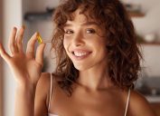 Diet. Nutrition. Healthy Eating, Lifestyle. Close Up Of Happy Smiling Woman Taking Pill With Cod Liver Oil Omega-3 In Morning. Vitamin D, E, A Fish Oil Capsules