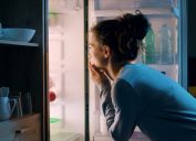 Woman looking in the fridge late at night, she is searching for a snack