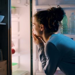 Woman looking in the fridge late at night, she is searching for a snack
