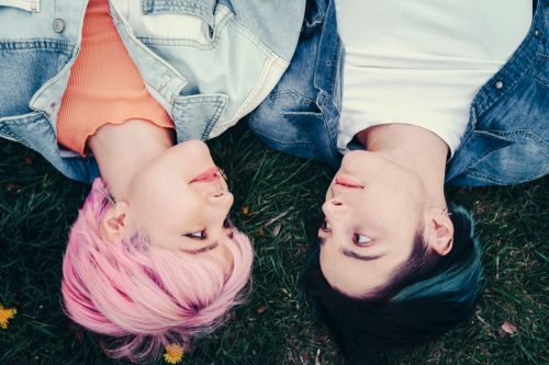 two young people laying in the grass and looking at each other