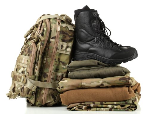 Army uniform piled up with boots on top, next to backpack