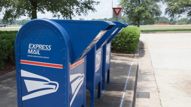 A trio of blue express mail mailboxes on a street