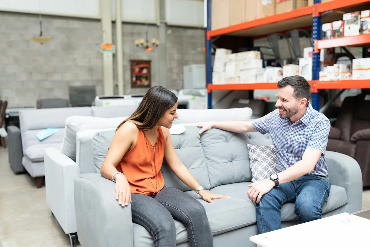 Happy couple sitting comfortably while examining sofa at warehouse store