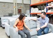 Happy couple sitting comfortably while examining sofa at warehouse store