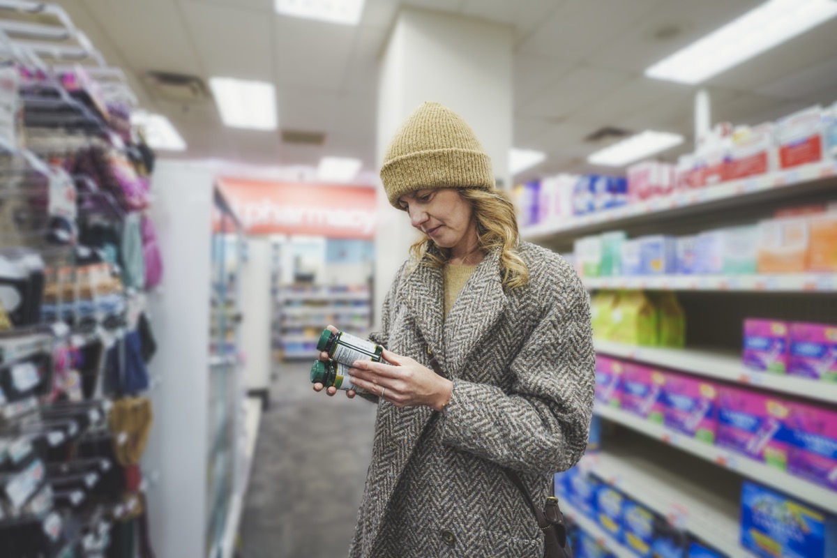 Woman shopping for multivitamins at pharmacy store