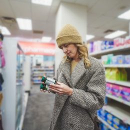 Woman shopping for multivitamins at pharmacy store