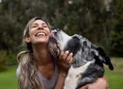 Happy woman playing with her dog outdoors