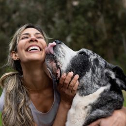 Happy woman playing with her dog outdoors