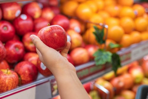 Human hand picking an apple when buying fruit at supermarket