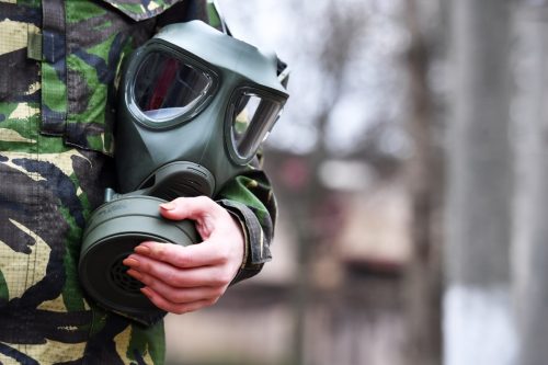 military member holding gas mask for protection against a chemical attack