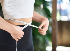 woman measuring herself for weight loss