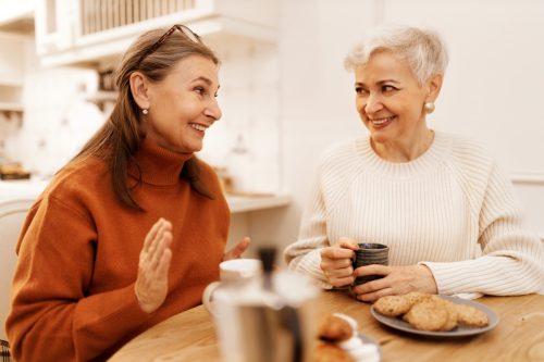 two mature women thinking of fun questions to ask each other at a cafe