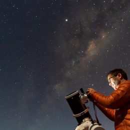 A person setting up a telescope to look at the night sky filled with stars