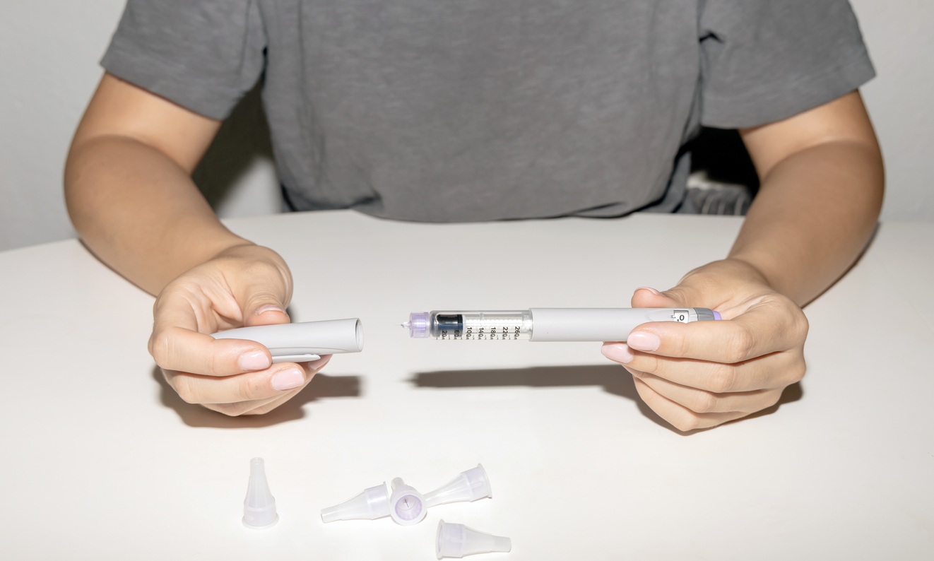 A close up of a person taking the cap off a weight loss drug injection needle