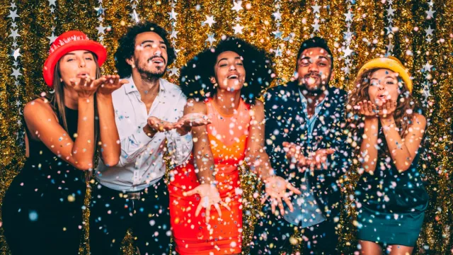 Friends blowing confetti at a new year's party.