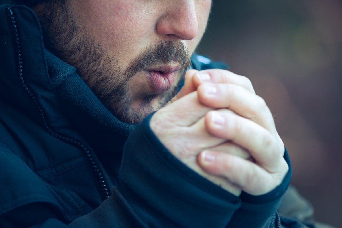 Man blowing in his hands, cold weather