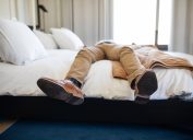 man relaxing on hotel bed with only his legs and feet showing