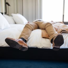 man relaxing on hotel bed with only his legs and feet showing