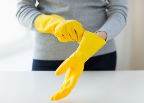 woman putting on yellow rubber gloves