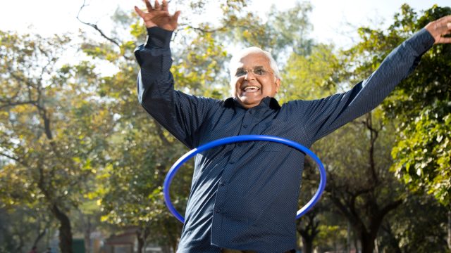 Happy senior man exercising with hula hoop at park