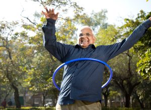 Happy senior man exercising with hula hoop at park