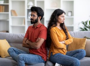 Unhappy young couple fighting on couch