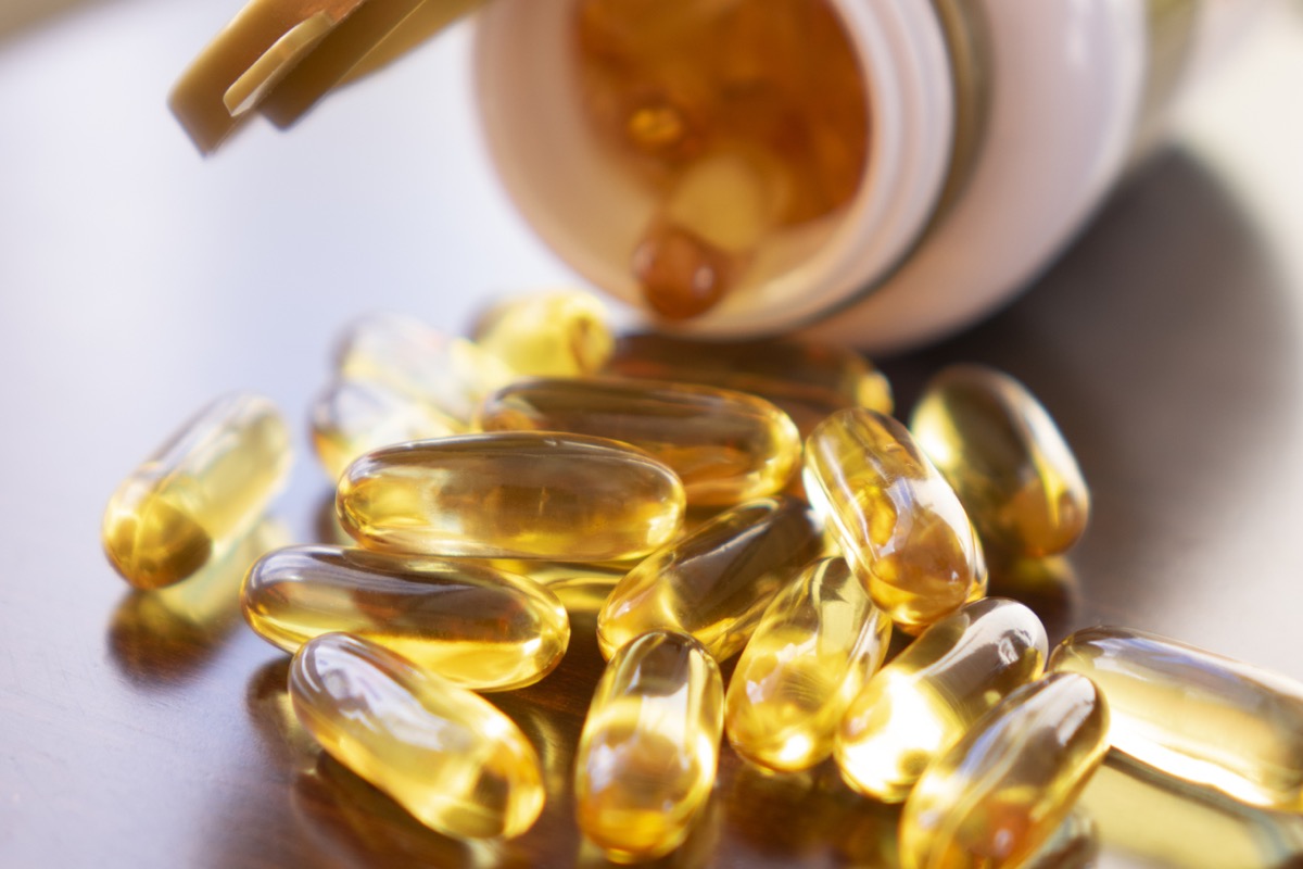 Fish oil capsules with omega 3 and vitamin D in a glass bottle on wooden texture, healthy diet concept,close up shot.