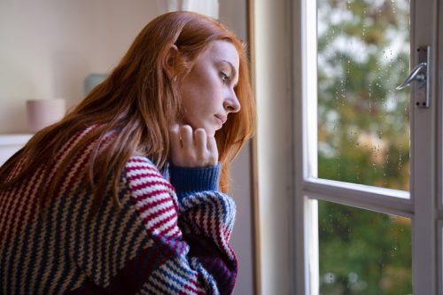 sad looking young woman gazing out the window