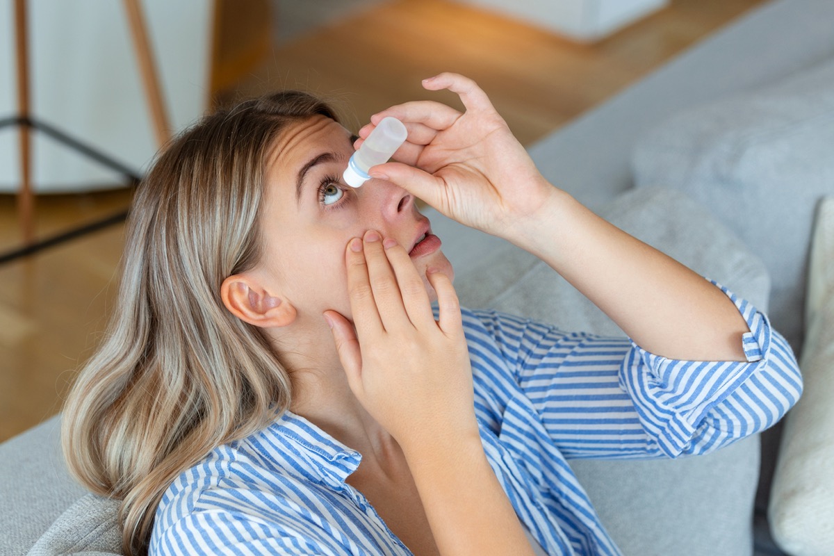 woman putting in eye drops at home