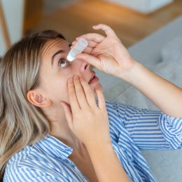 woman putting in eye drops at home
